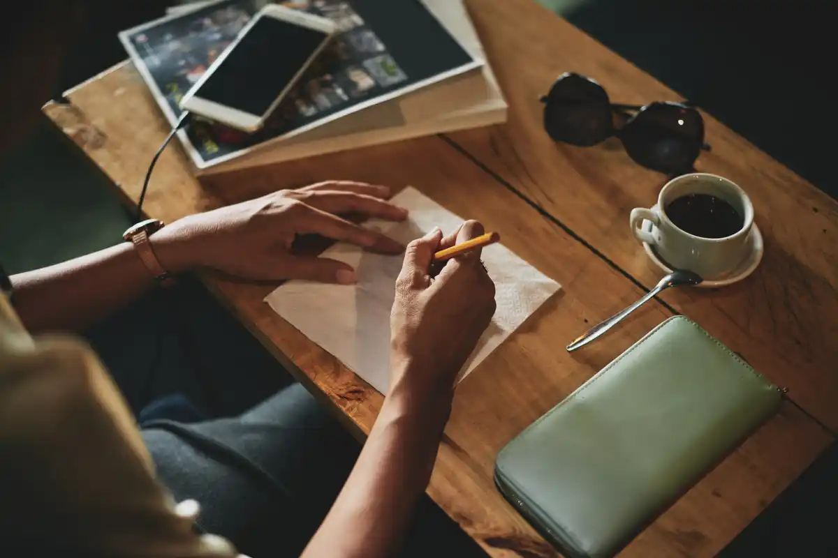 person writing with reed pen on ancient papyrus sheet