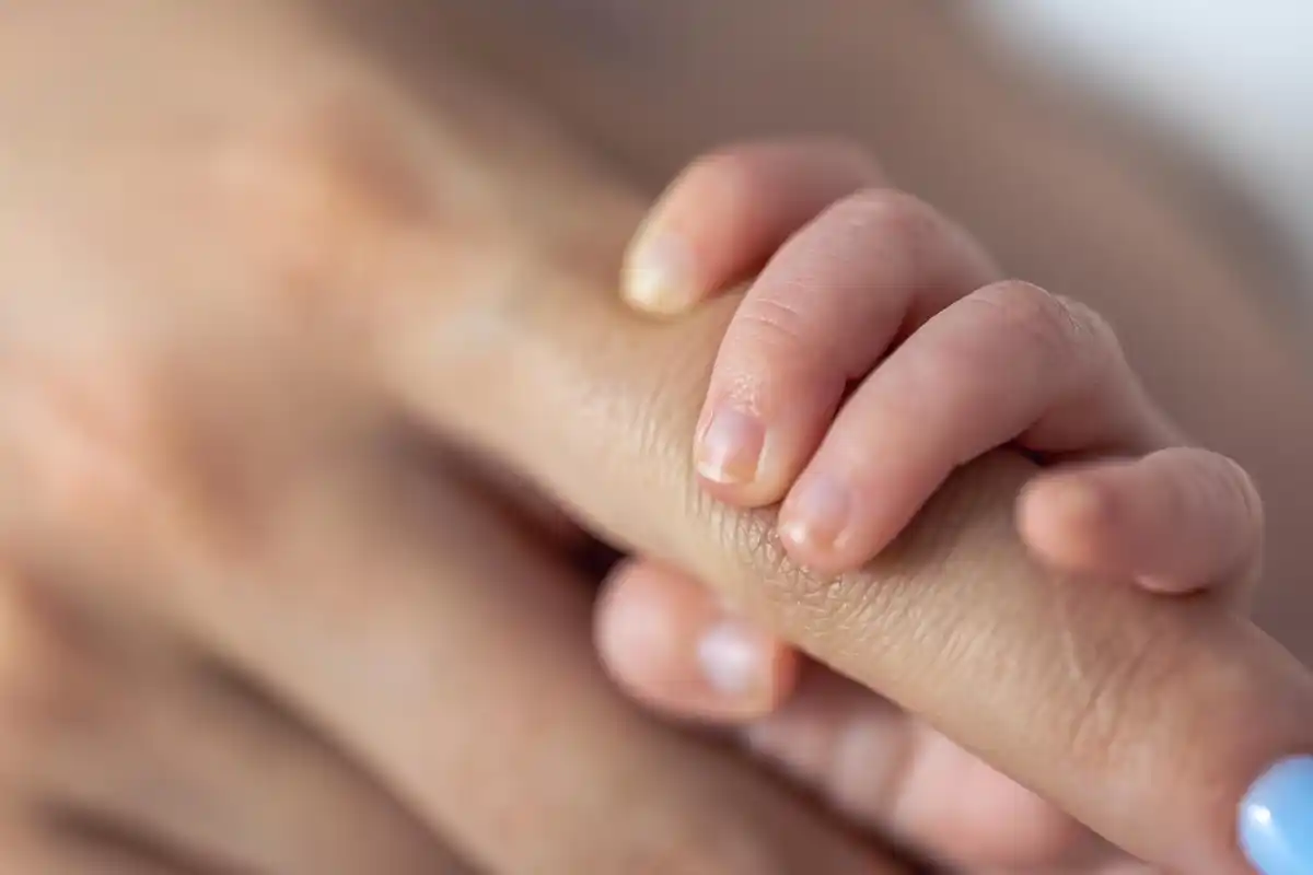 newborn baby hand gripping adult finger close-up