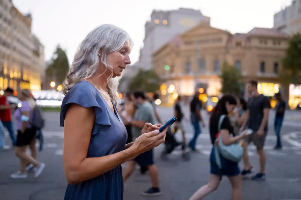 Dutch senior citizen using flip phone outdoors