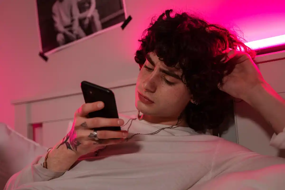 Person lying in bed scrolling phone at night